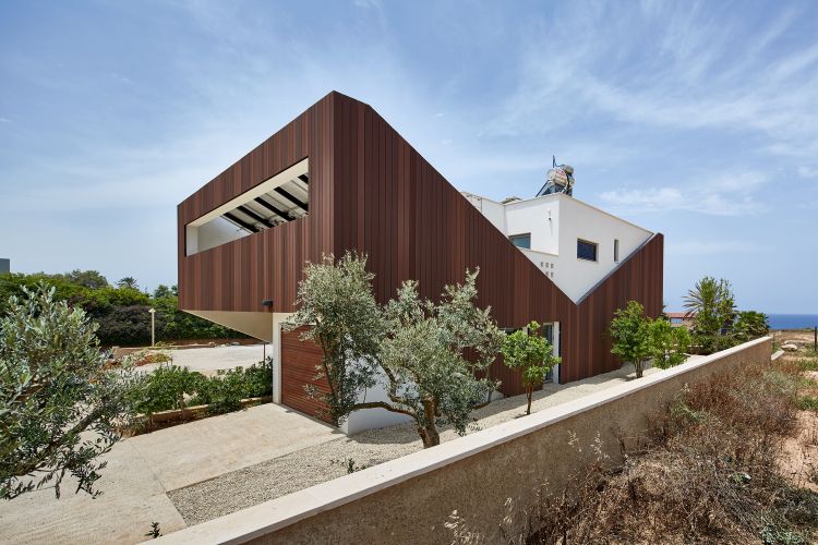 casa feita de material reciclado eco360 construção sustentável eficiência casa mais casa da energia mais casa da energia fachada tiras de madeira em forma de v vista lateral para o mar