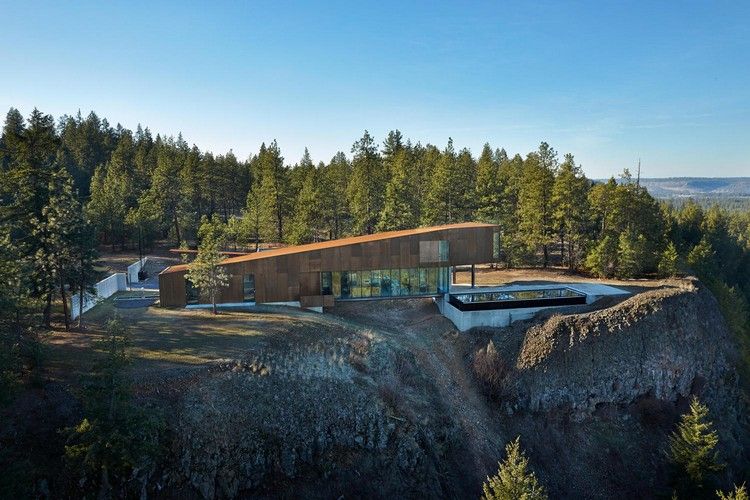 casa em afloramento rochoso fachada piscina infinita vidro de aço ascendente