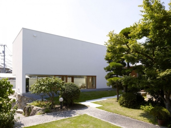 casa no jardim construída em torno de uma fachada branca de árvore