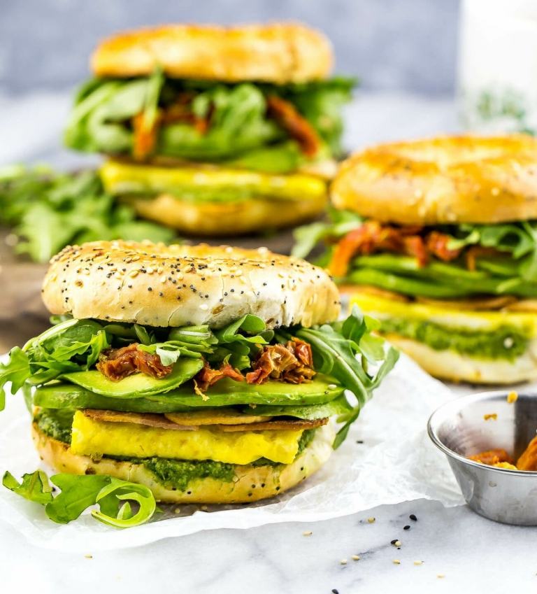 Sanduíche feito de bagel com pesto, rúcula e carne