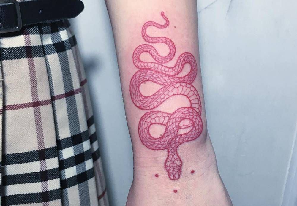 Uma serpente sinuosa em vermelho como uma tatuagem no antebraço para mulheres