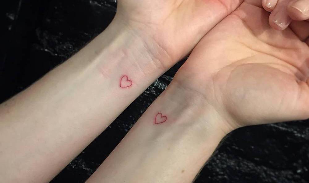 Micro-tatuagem com corações vermelhos no pulso como uma ideia para tatuagens de parceiros