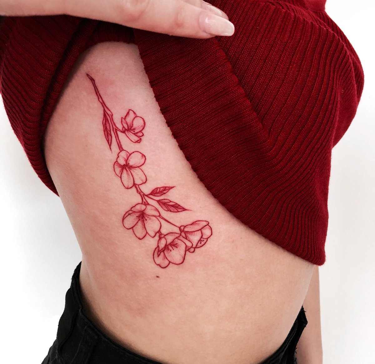 Tatuagens vermelhas para mulheres com flores na caixa torácica