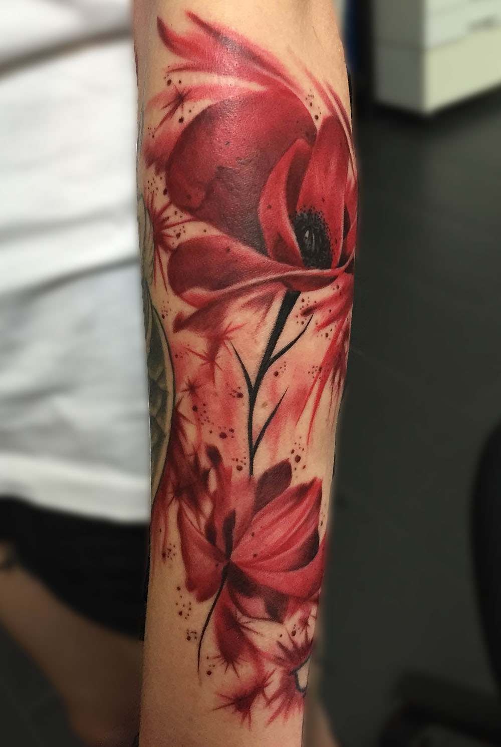 Tatuagens com efeito aquarela vermelho para flores no braço