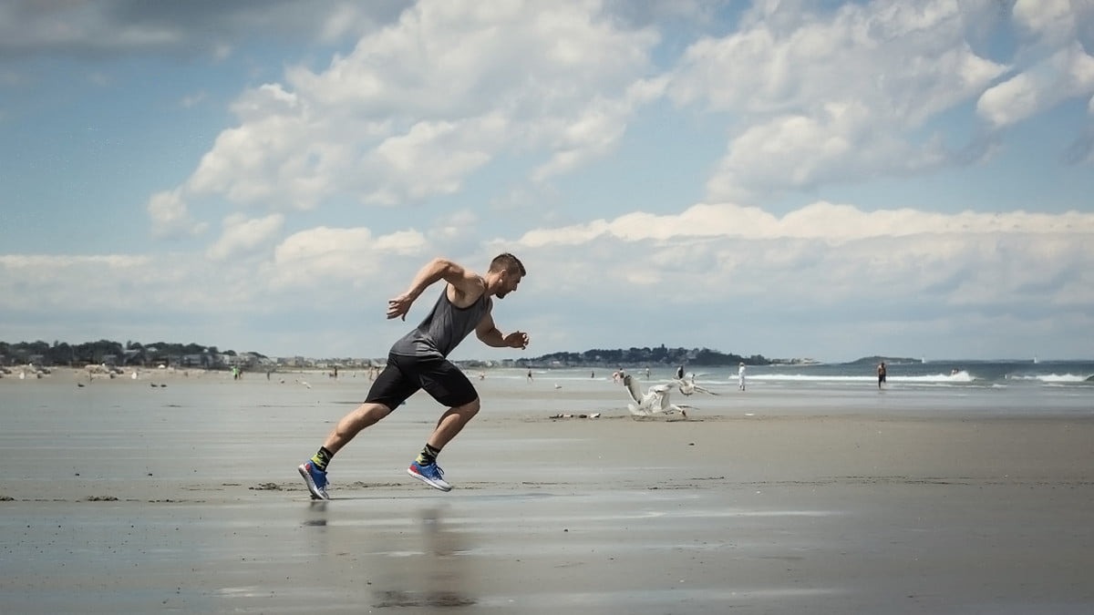 Atleta de musculação na praia treino com sprint